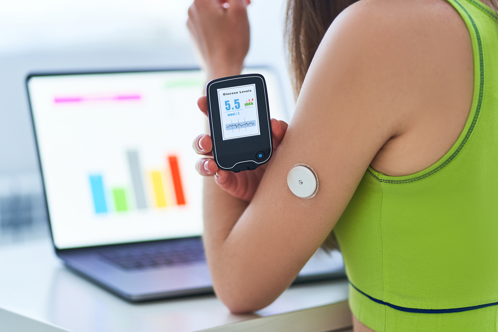 Woman checking glucose monitor on arm