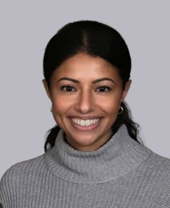 Professional headshot of Dr. Farida Migally, MD, wearing a gray turtleneck sweater and smiling against a light gray background.