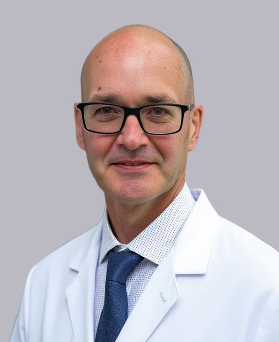 Professional headshot of Dr. Hammill, MD, MCR, FACS, wearing glasses, a white coat, and a blue tie, smiling against a light gray background.