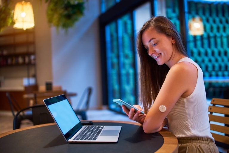Woman using modern glucose monitor connected to laptop